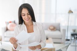 Woman at home reading a new employee welcome letter from her new employer.