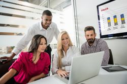 4 coworkers studying a checklist on a laptop