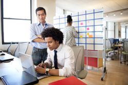 Boss looking over an employee's shoulder in office