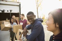 Smiling volunteers unloading cardboard boxes from truck