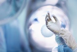 Surgeon adjusting glove in operating room