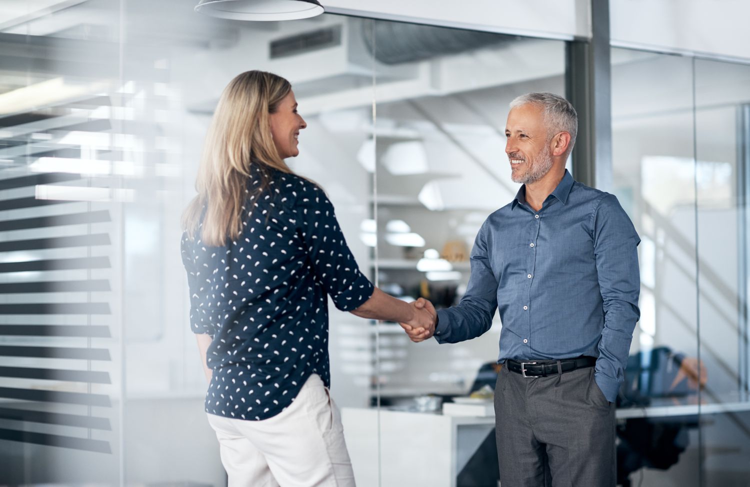 Man and woman shaking hands in a business office.