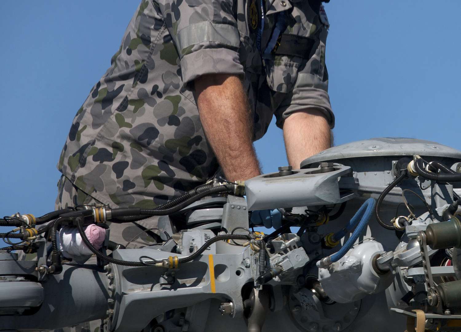 An Army armament/electrical/avionic systems repairer working on parts of a helicopter's rotor.