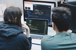 Rear view of computer programmers using laptop at office desk