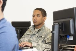 Black soldier using computer in class